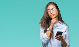 Femme qui réfléchit à appeler un DRH à temps partagé, en free-lance, un DRH de transition ou une équipe RH externe pour travailler avec les TPT PME